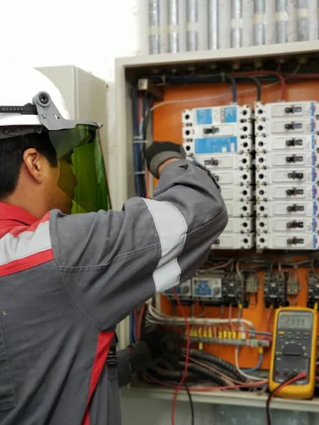 Electrician testing a breaker panel with a multimeter