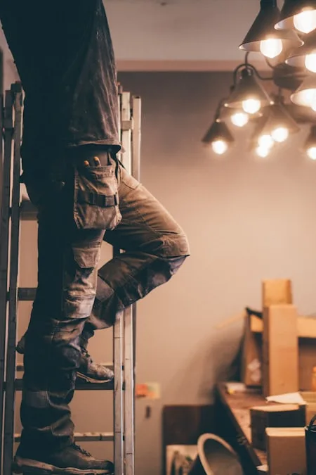 Electrician on a ladder wiring a light fixture