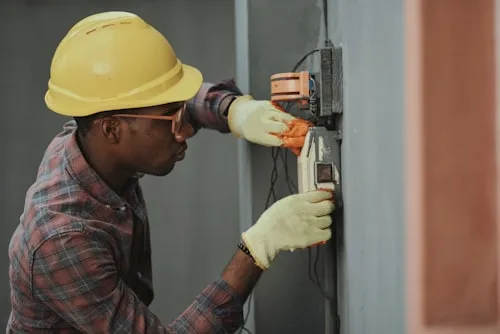 Electrician in a hard hat wiring an exterior panel
